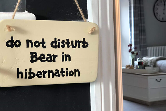 do not disturb bedroom sign hanging on door with bed.