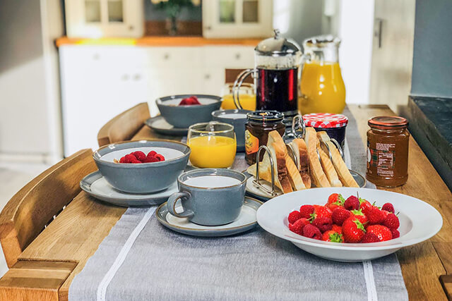 welcome hamper on kitchen table with strawberries, juices, coffee, toast.