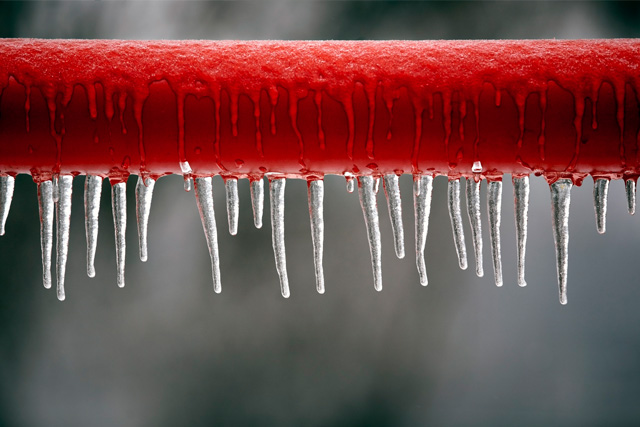Red frozen pipe with icicles on it