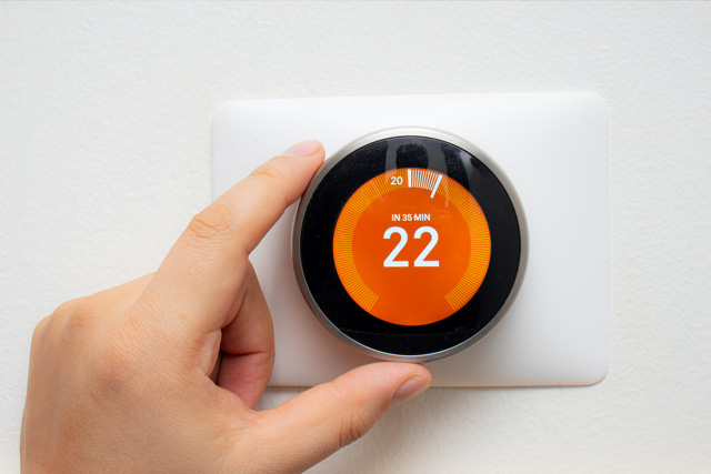 Hand turning up smart thermostat