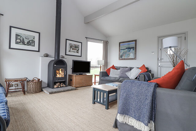 Holiday let lounge with logburner, tv, sofa and atlantic blanket.