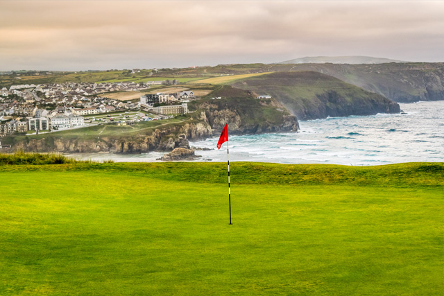 View of the sea beyond Perranporth Golf Club, with a red flag in the foreground