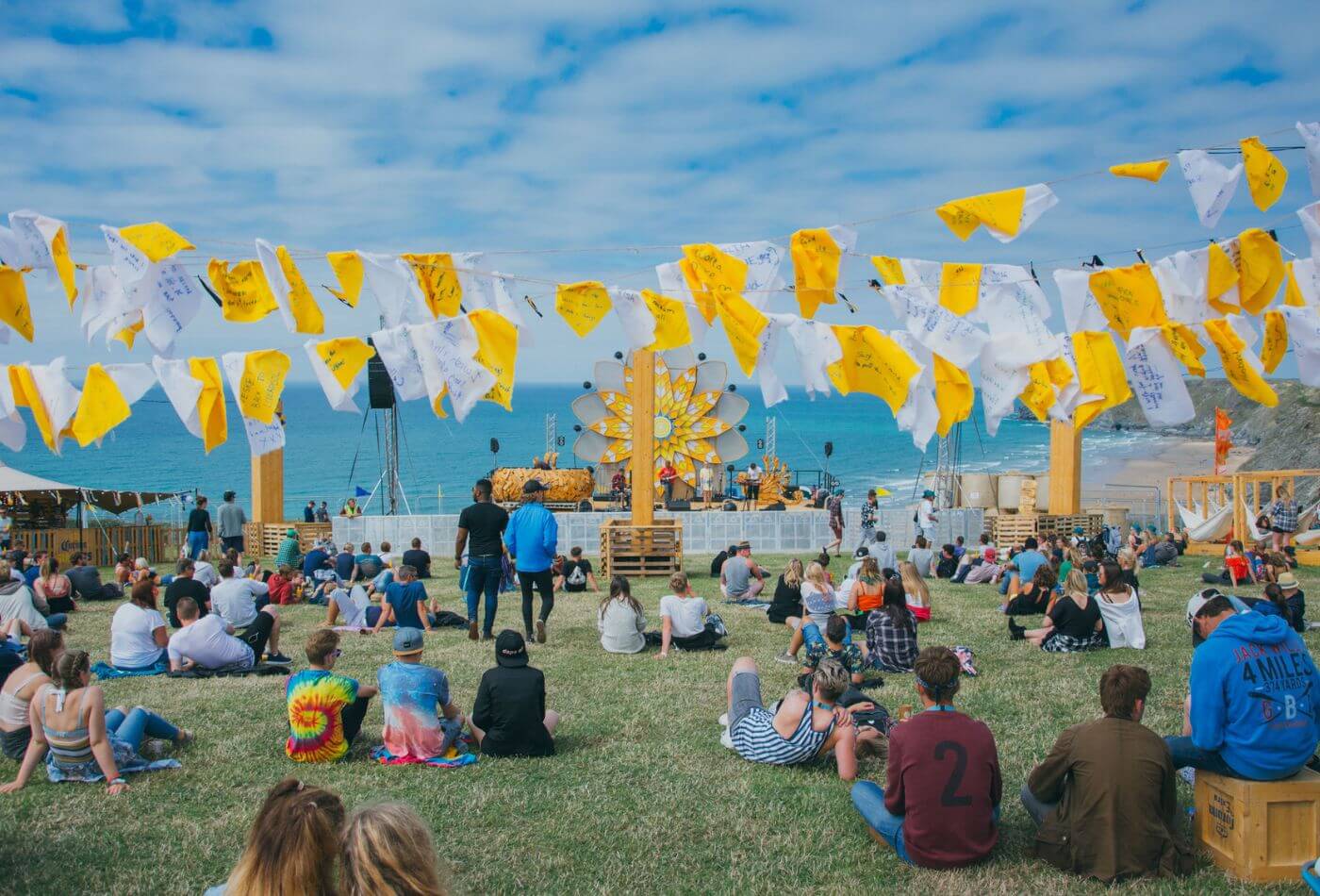 A crowd at Boardmasters Festival in Newquay beneath yellow flags.