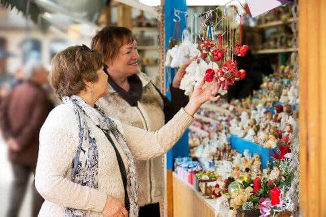 Two women browsing a Christmas market stall.
