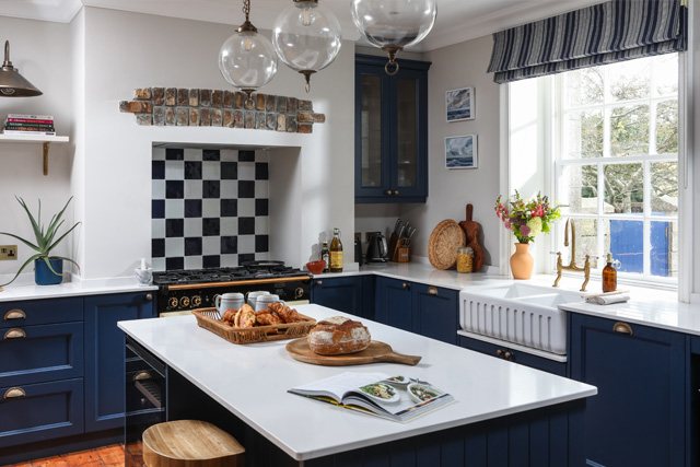 A kitchen with white walls and dark blue units, designed by Studio Far West