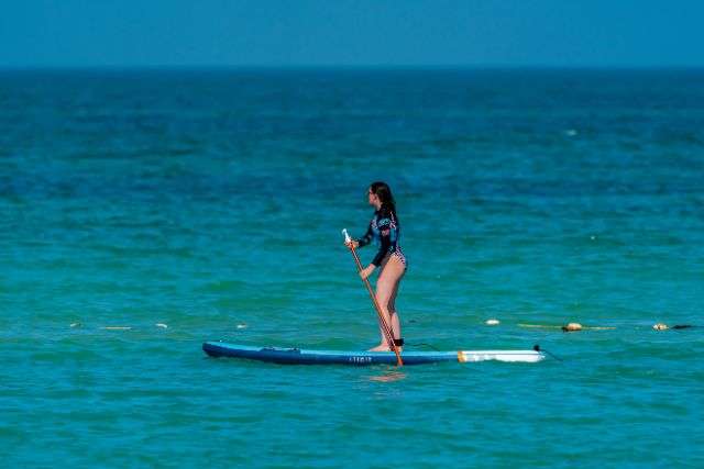 Woman paddleboarding on blue sea