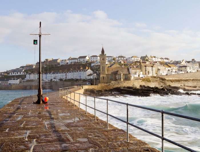 View along Porthleven harbour, with white harbour alongside, on a sunny day