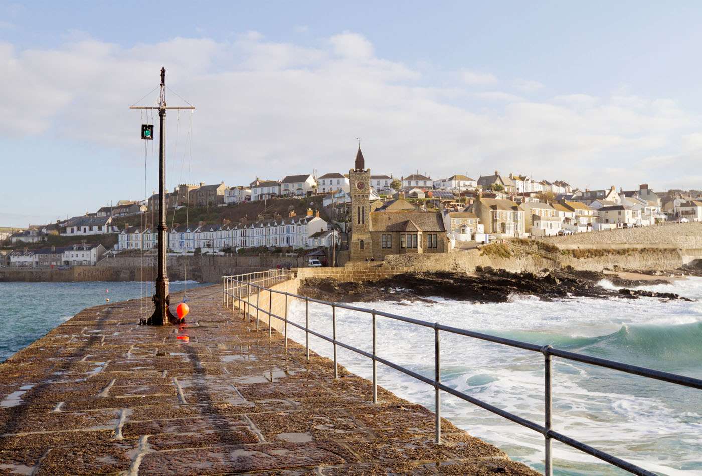 View along Porthleven harbour, with white harbour alongside, on a sunny day